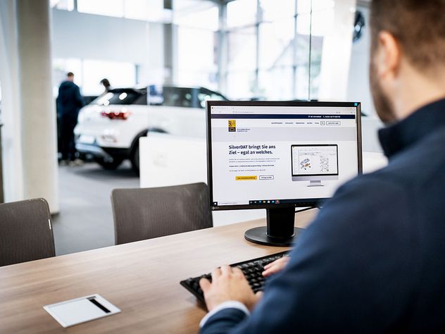Mann sitzt im Autohaus an einem Rechner und nutzt eine Software