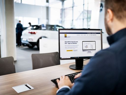 Mann sitzt im Autohaus an einem Rechner und nutzt eine Software