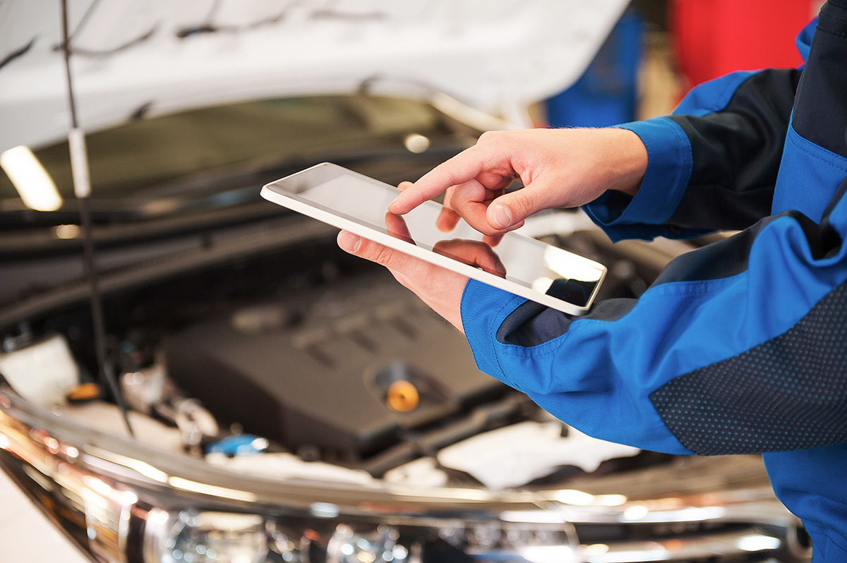 Kfz-Mechatroniker mit Tablet an Auto mit geöffneter Motorhaube: Auch kleineren KFZ-WErkstätten steht in SilverDAT 3 eine digitale Schadenakte zur Verfügung