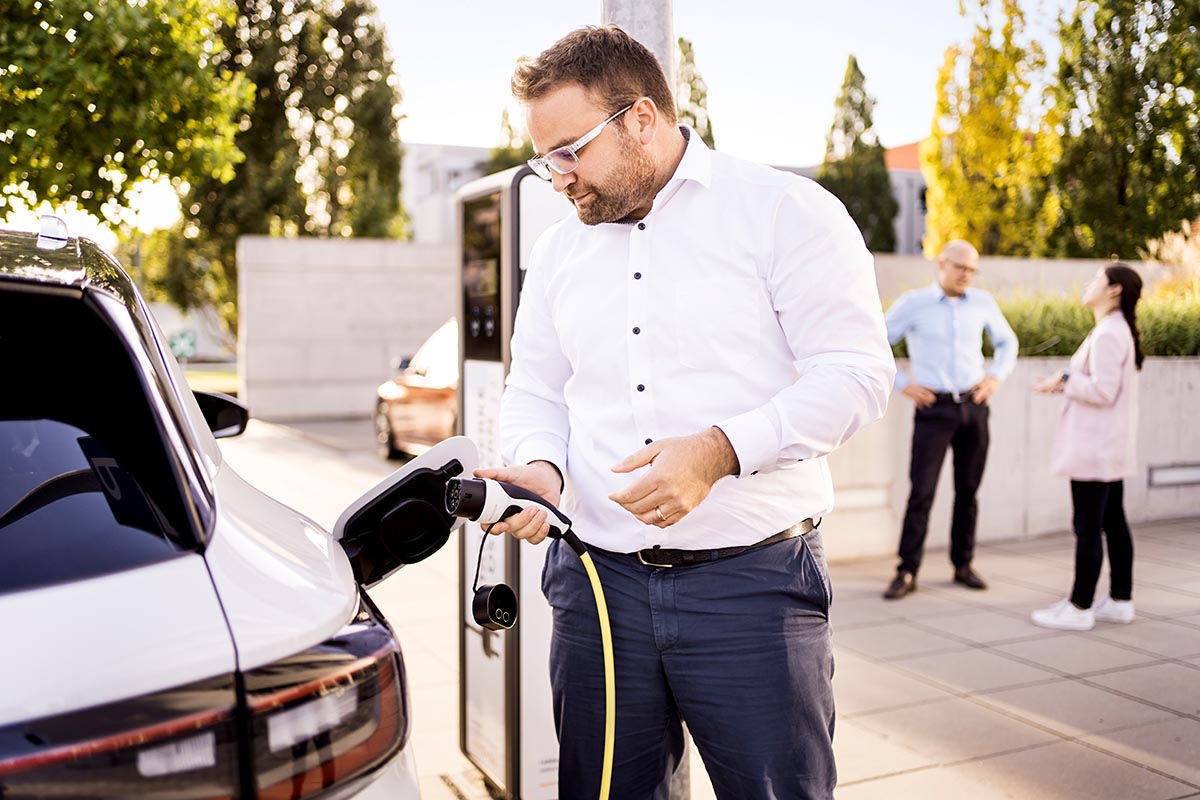 Man with AC charging cable at charger: What impact does the battery health have on the price of a used EV?