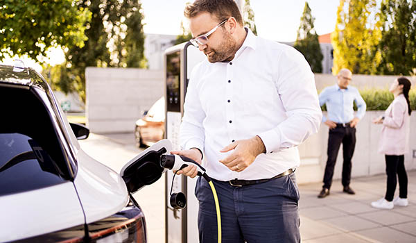 Man with AC charging cable at charger: What impact does the battery health have on the price of a used EV?